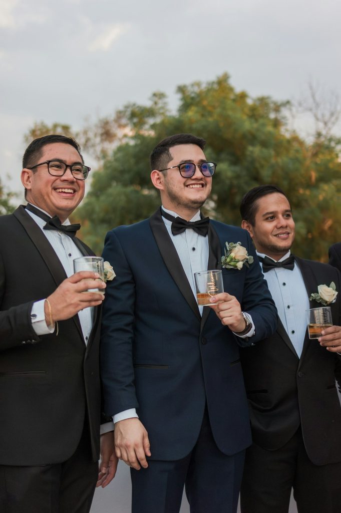 a-group-of-men-standing-next-to-each-other-holding-wine-glasses-r-xvyhqrbik