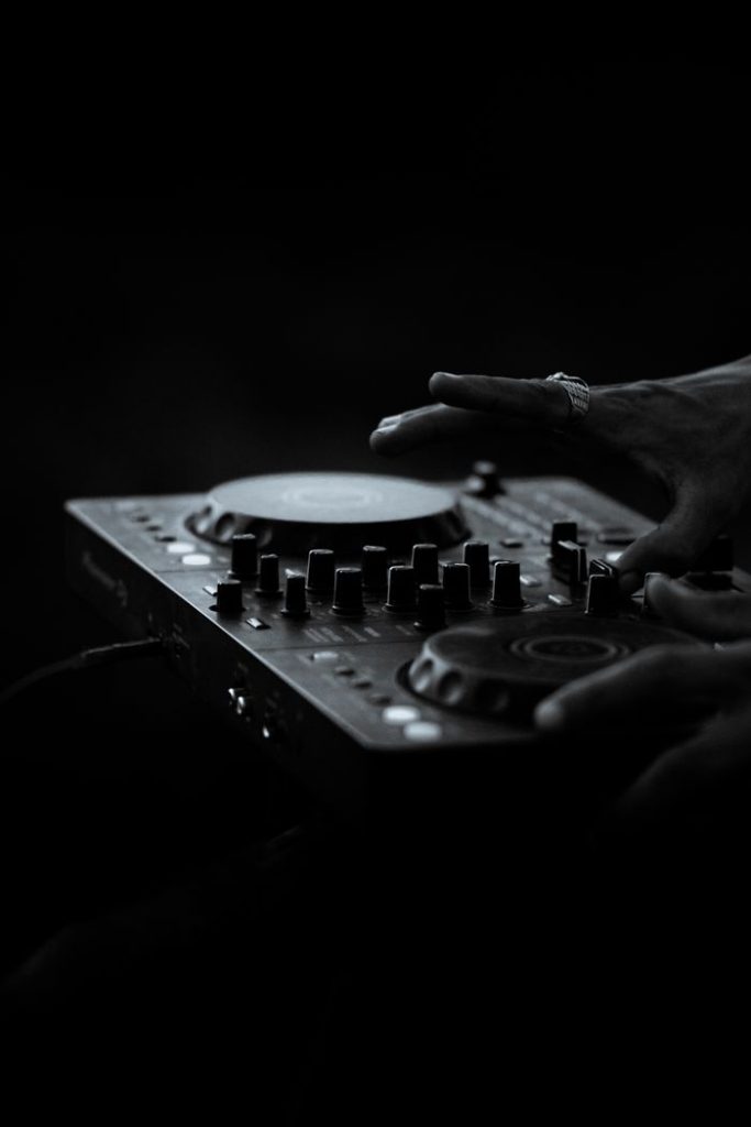 DJ using a mixing console in low light setting. Perfect for music and nightlife imagery.