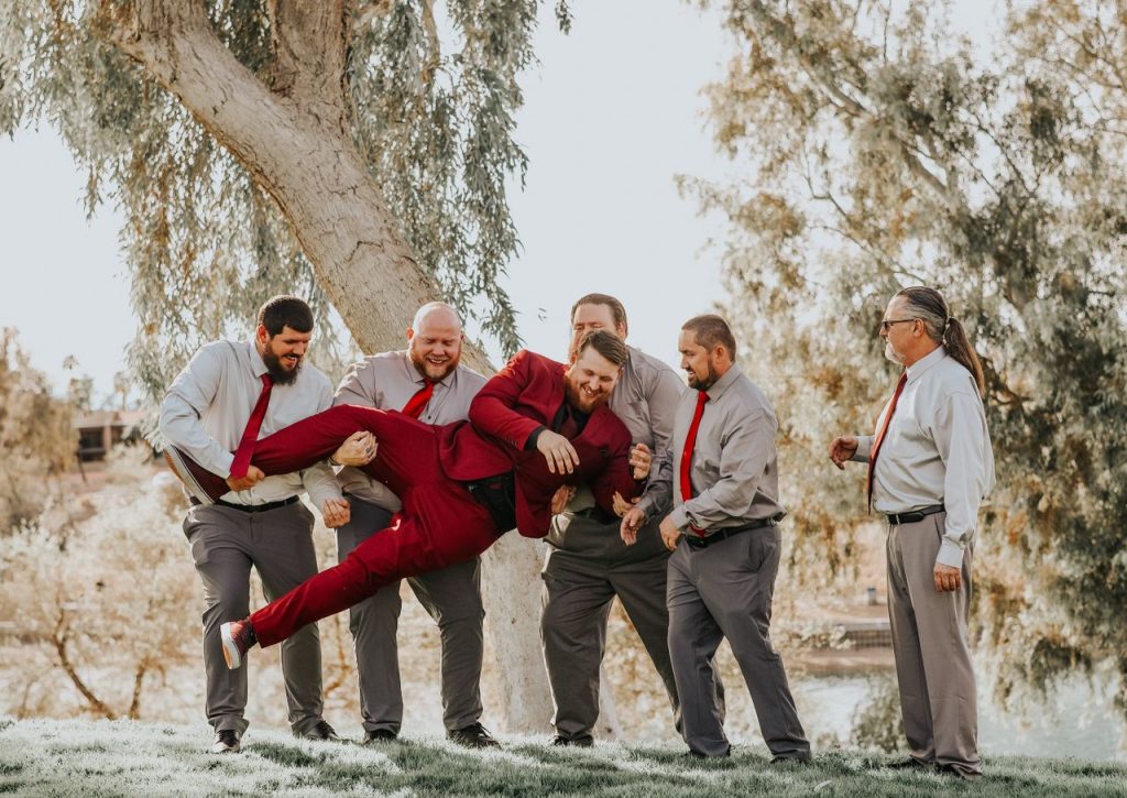Group of men in suits having fun outdoors during a celebration.